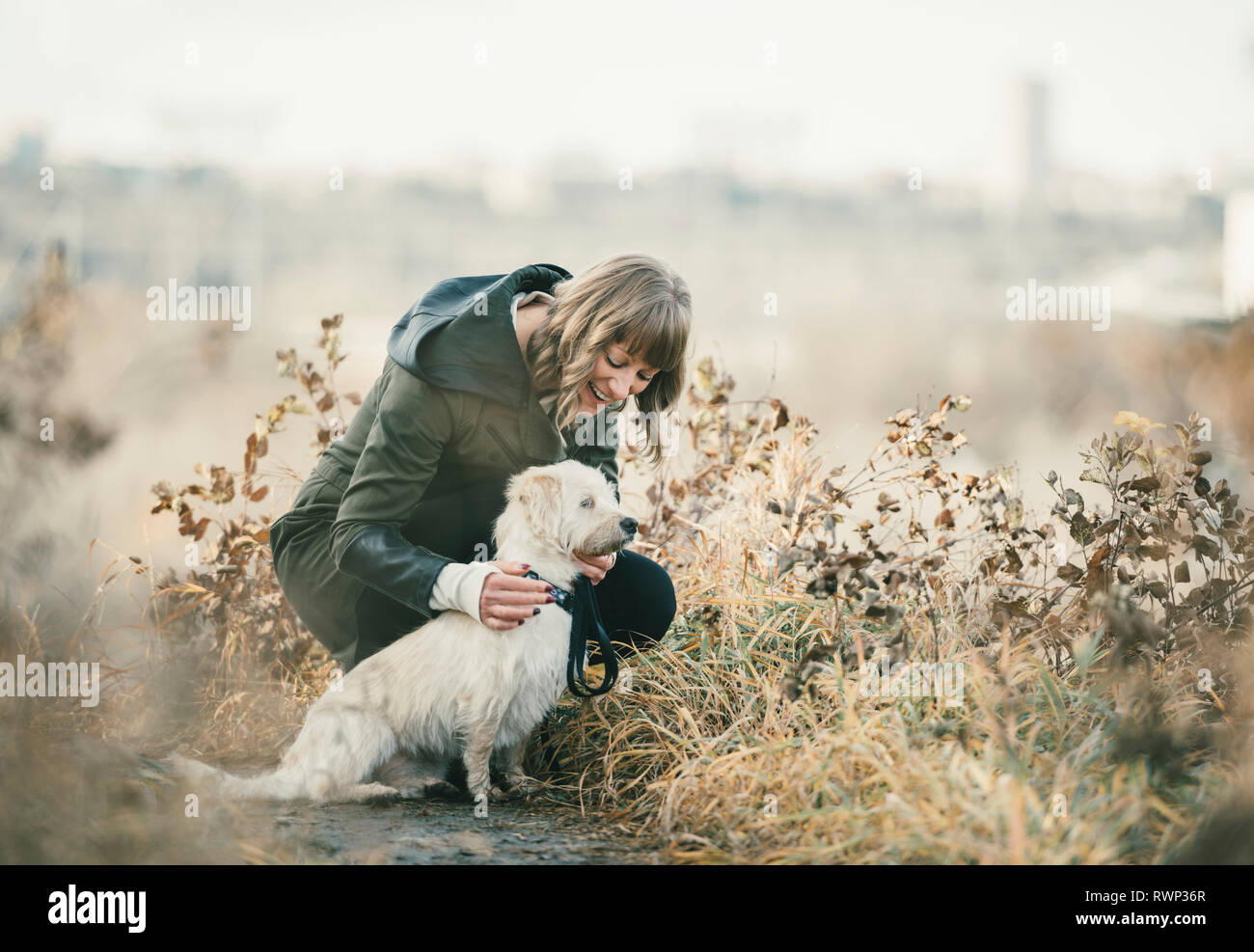 Woman walking her dog with a city skyline in the background; Edmonton