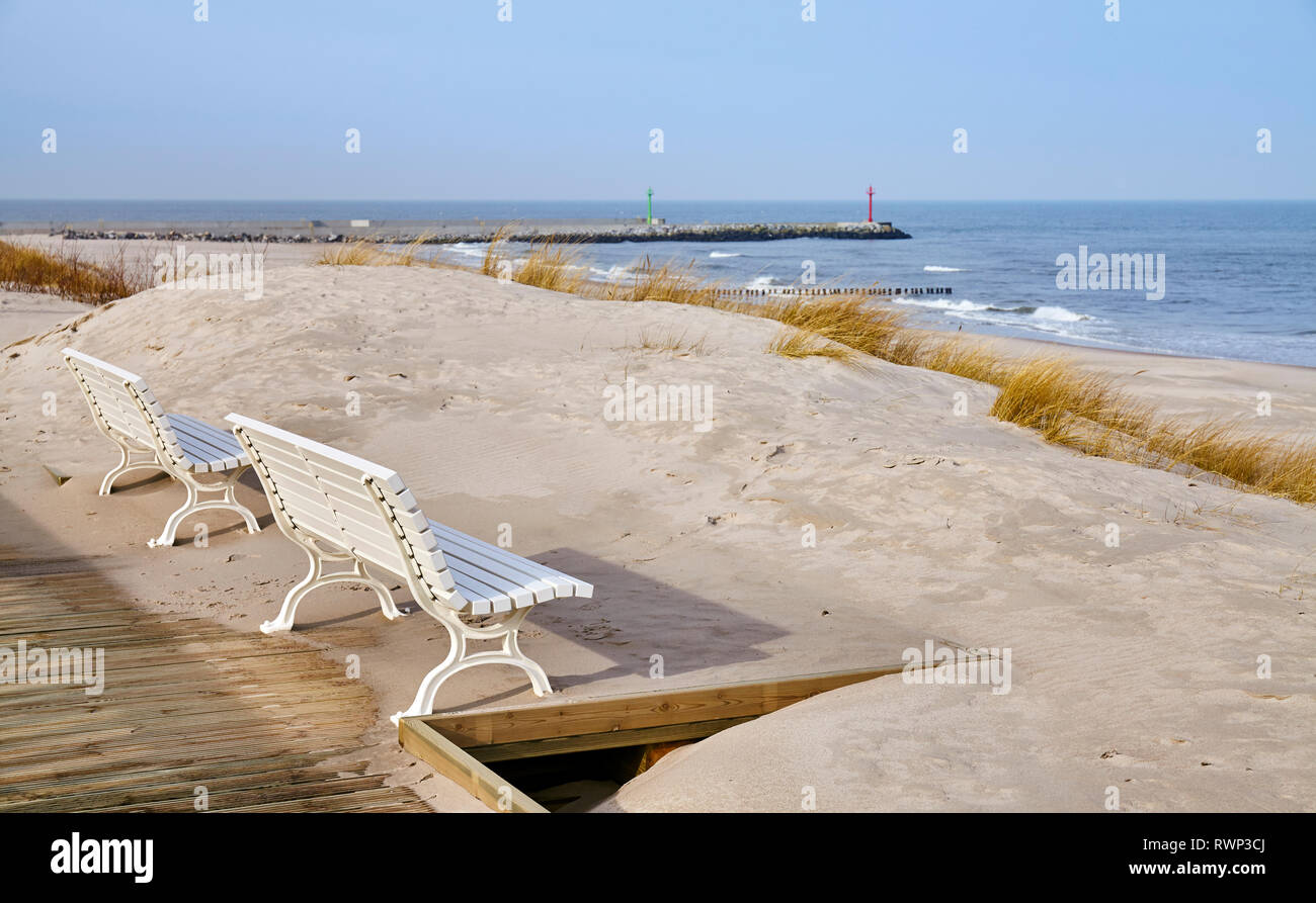 Benches along a sea view wooden boardwalk, selective focus. Stock Photo