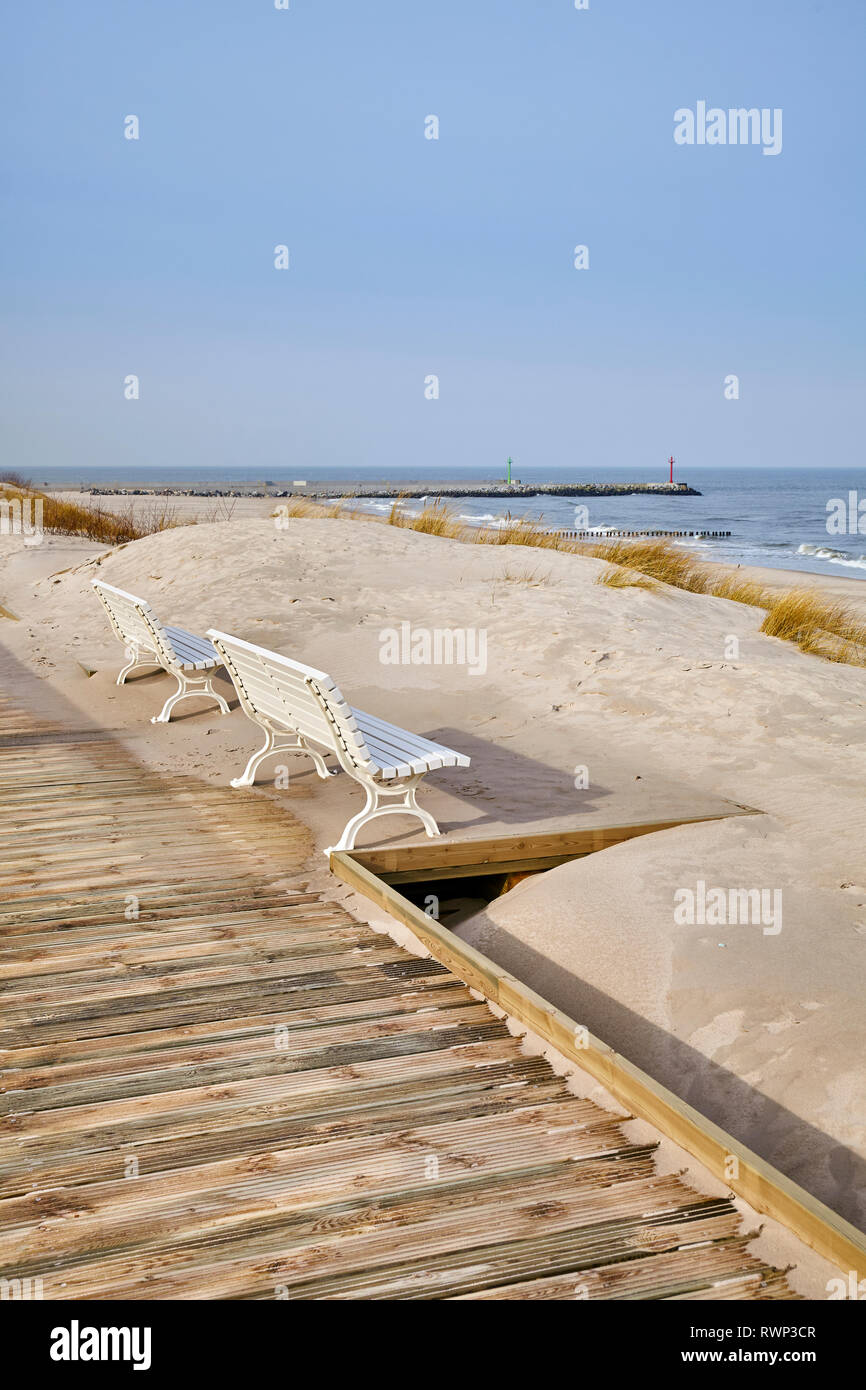 Benches along a sea view wooden boardwalk on a sunny day. Stock Photo