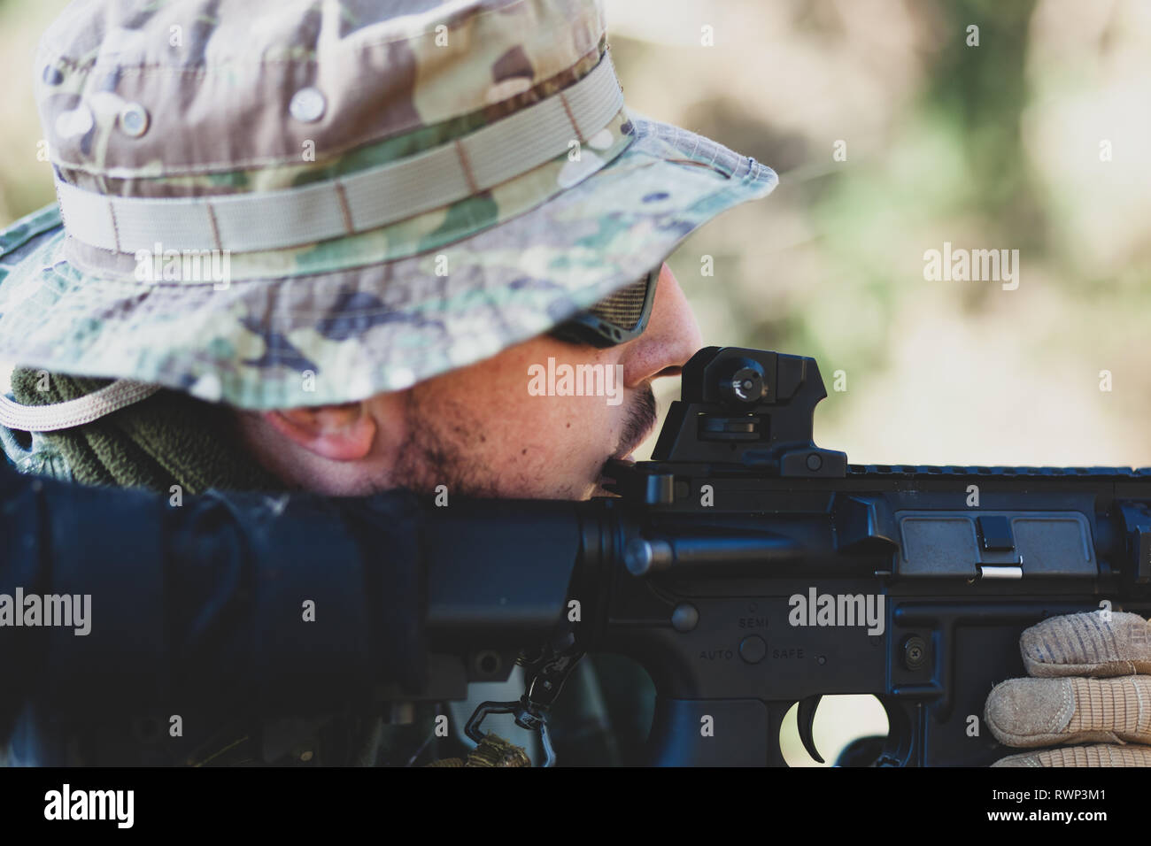 Airsoft military game player in camouflage uniform with armed assault rifle. Stock Photo