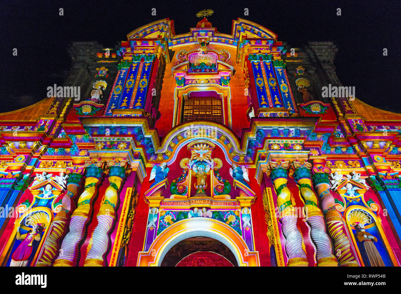 The baroque style facade of the Jesuit church of the Compania de Jesus illuminated with colours in the historic city center of Quito, Ecuador. Stock Photo