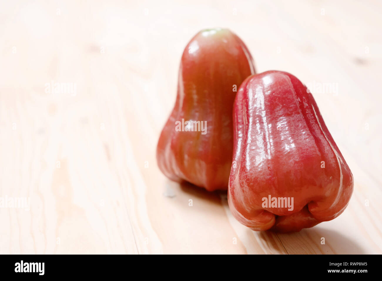Syzygium is a genus of flowering plants. That can be eaten. Close up two rose apple on the wooden table with copy space. Stock Photo