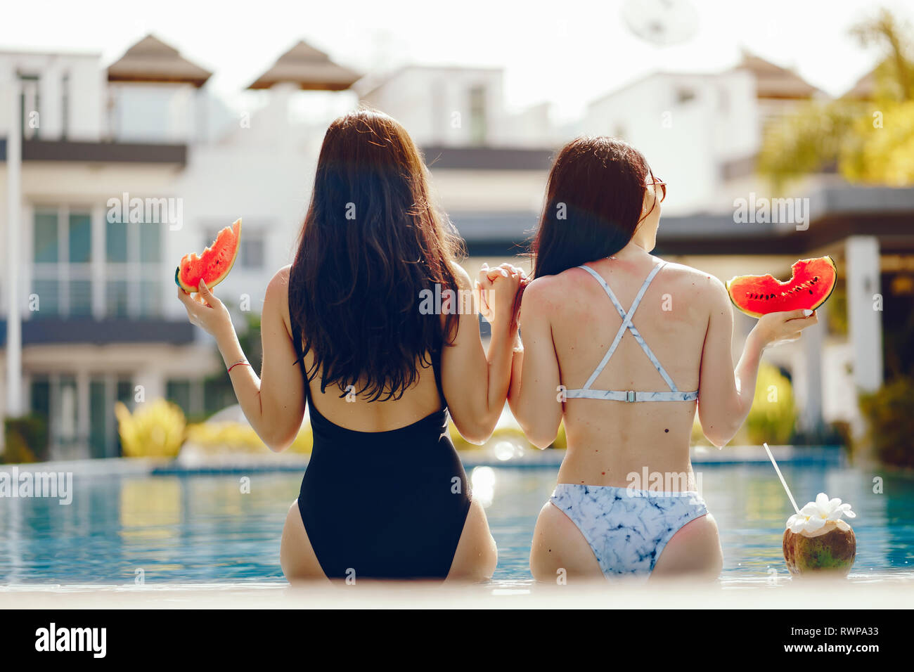 two girls having fruit by the pool Stock Photo