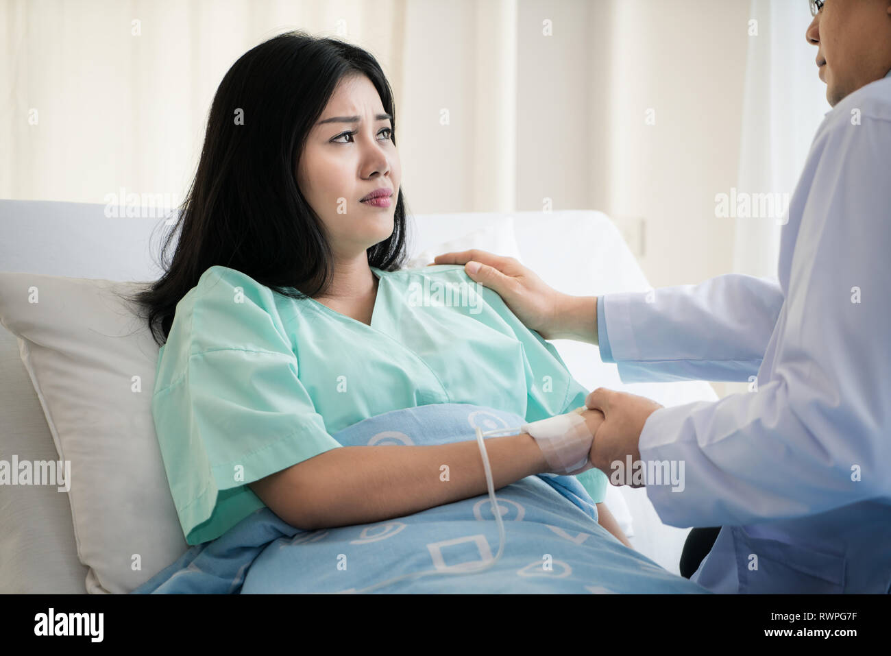 Friendly man doctor hands holding patient hand sitting at the desk for encouragement, empathy, cheering and support while medical examination. Bad new Stock Photo