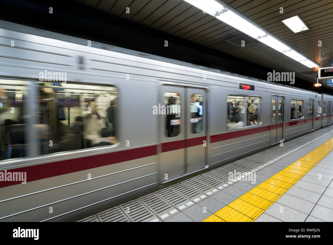 Interior of a Tokyo subway station and platform with subway commuters in Tokyo, Japan. Stock Photo