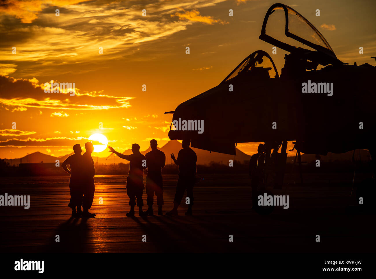 The sun sets behind  A-10 Demonstration Team maintenance crew members during the Heritage Flight Training Course at Davis-Monthan Air Force Base, Ariz., Feb. 28,  2019. The team flew several sorties in preparation for the five-day course. (U.S. Air Force photo by Senior Airman Alexander Cook) Stock Photo