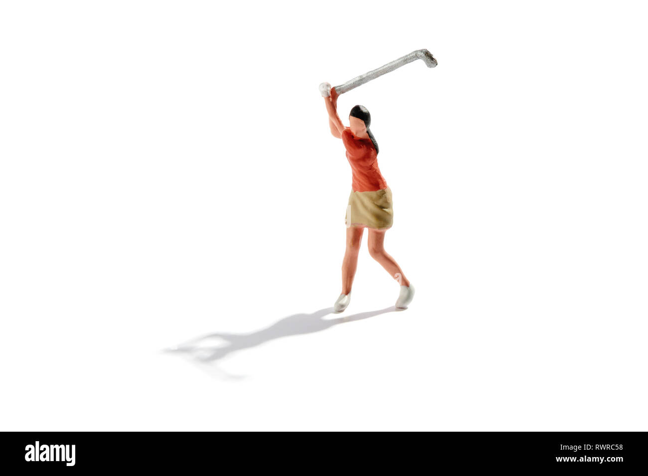 Miniature young girl playing golf swinging back her club to play the stroke isolated on white with backlit shadow and copy space Stock Photo