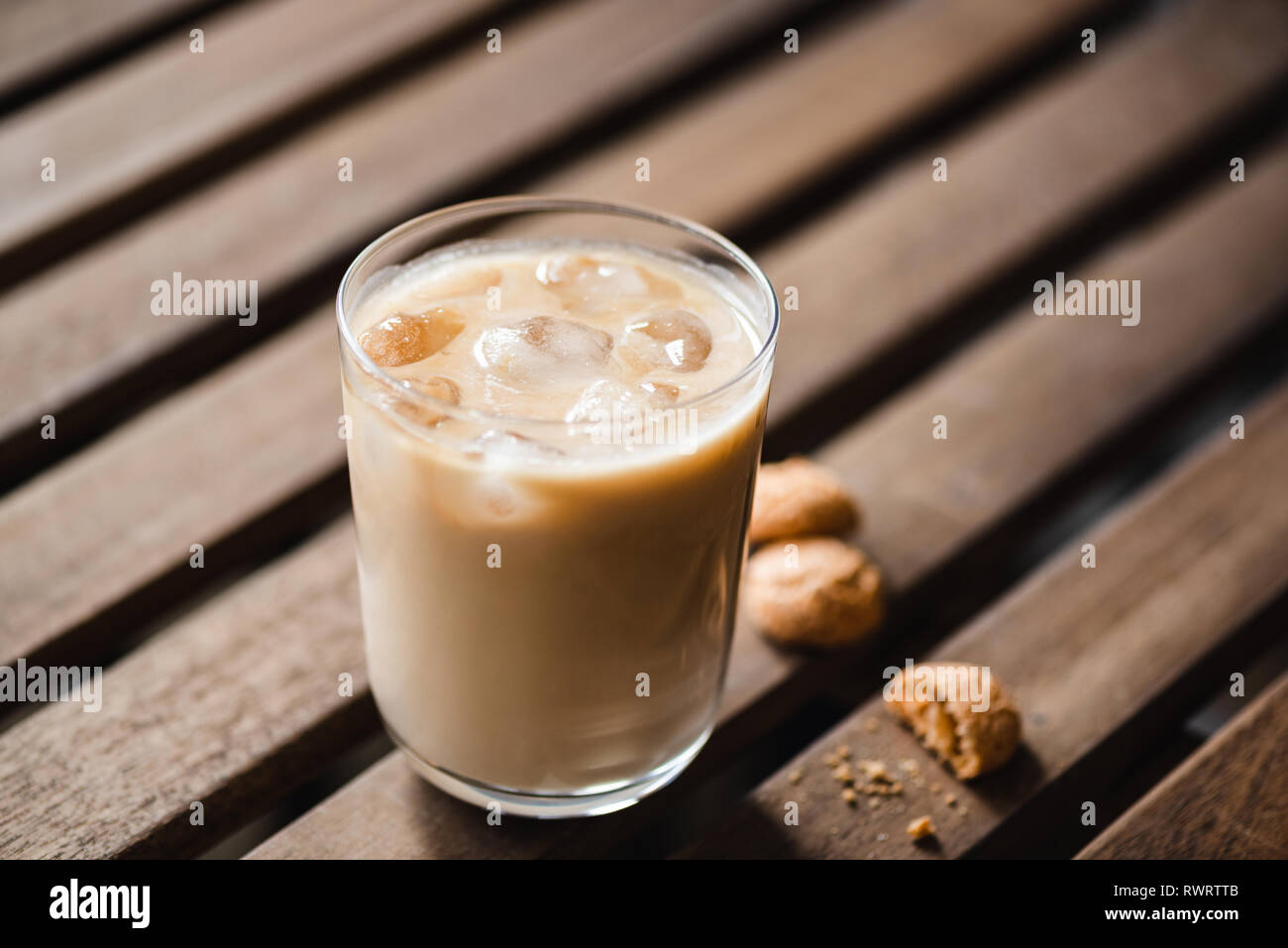 Ice latte in glass and amaretti cookies on wooden table. Morning drink Stock Photo