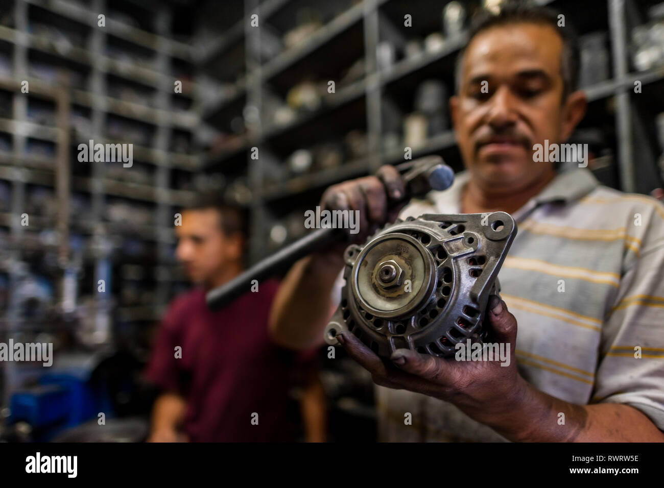 A Colombian car mechanic works on an alternator in a car repair shop in