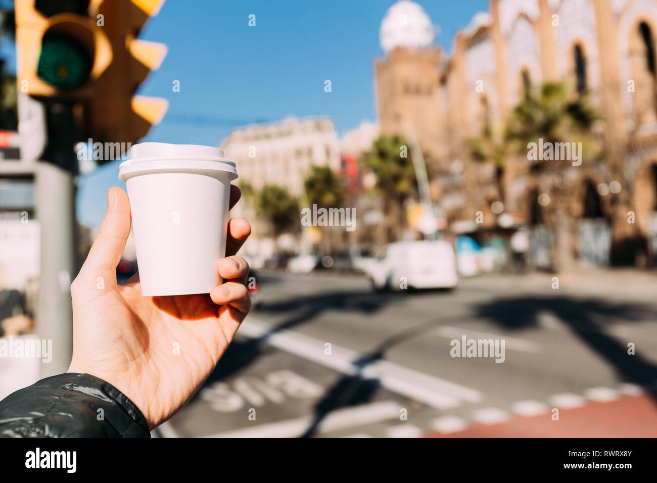 selective focus of man holding paper cup with urban scene on background ...