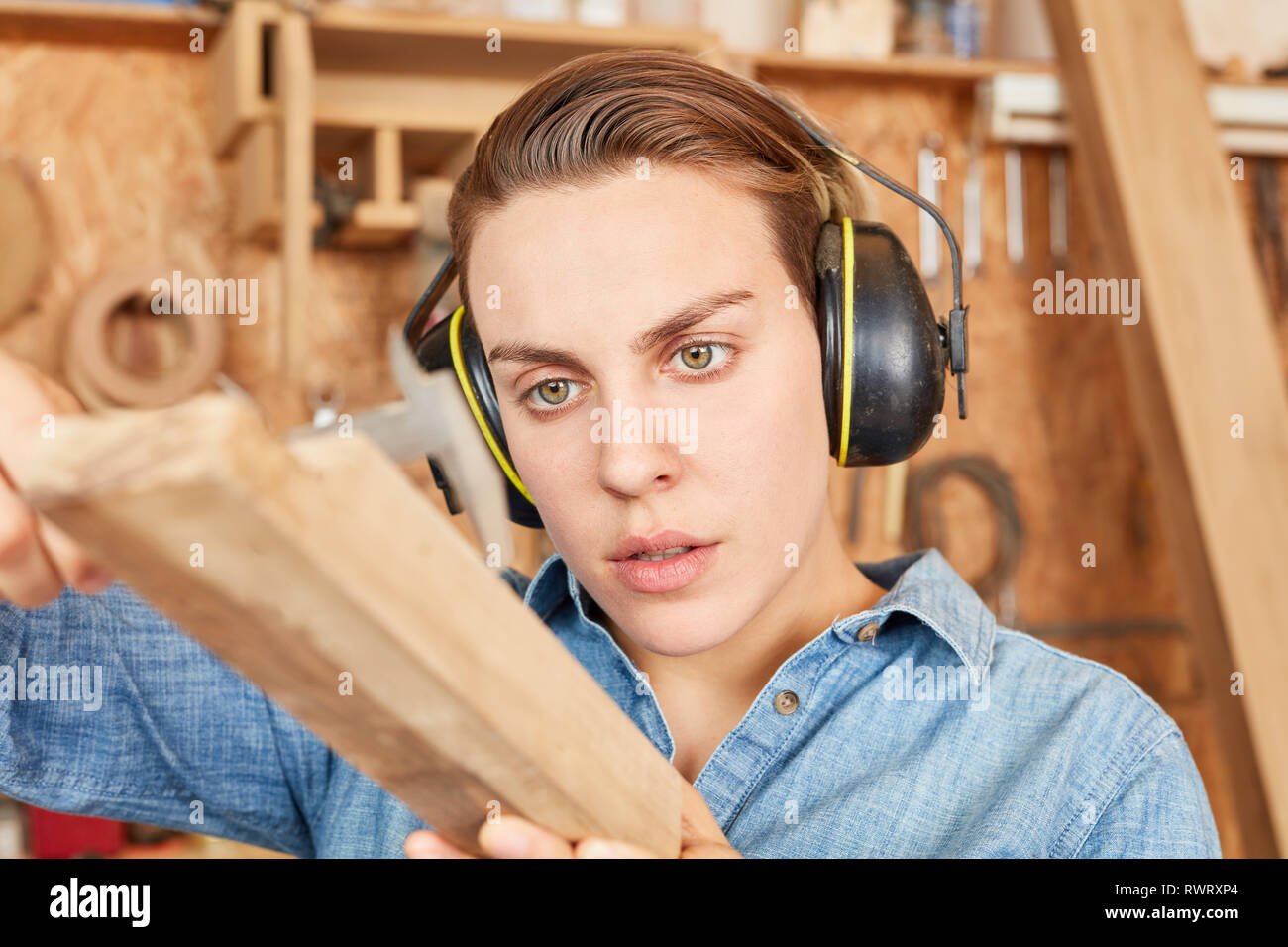 Young woman as a joiner trainee controls wood thickness with a gauge Stock Photo