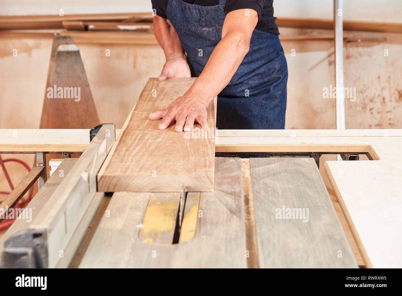 Carpenter saws a wood board at the circular saw in the joinery or