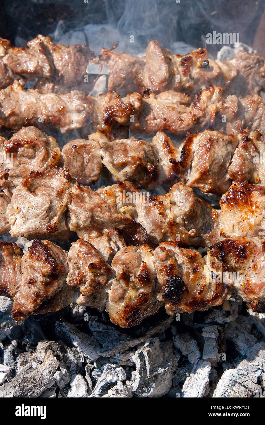 Grilled kebab cooking on metal skewer. Shashlik made of cubes of meat