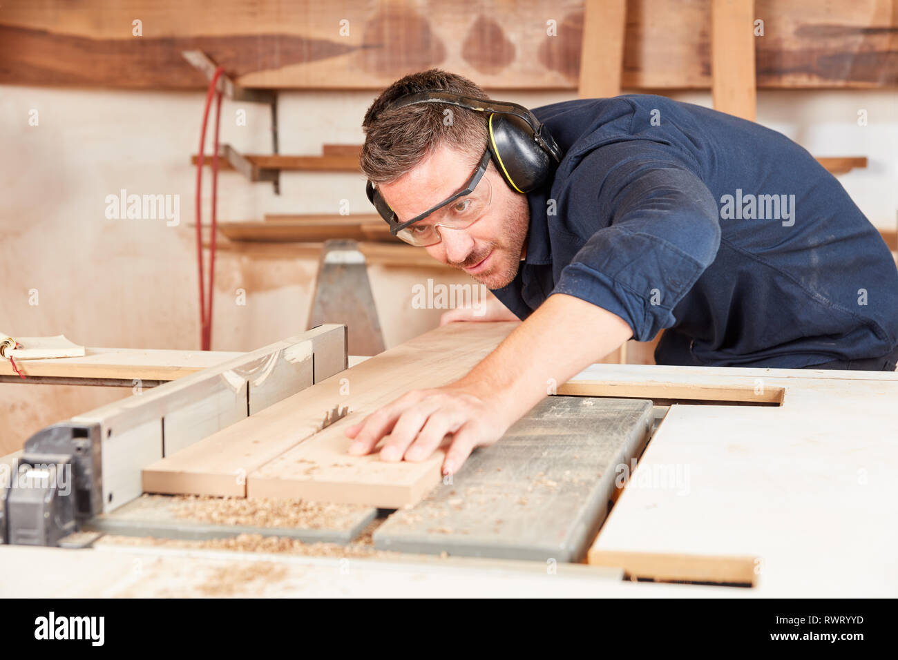 Man as a carpenter concentrically saws wood with the circular saw in the furniture carpentry Stock Photo