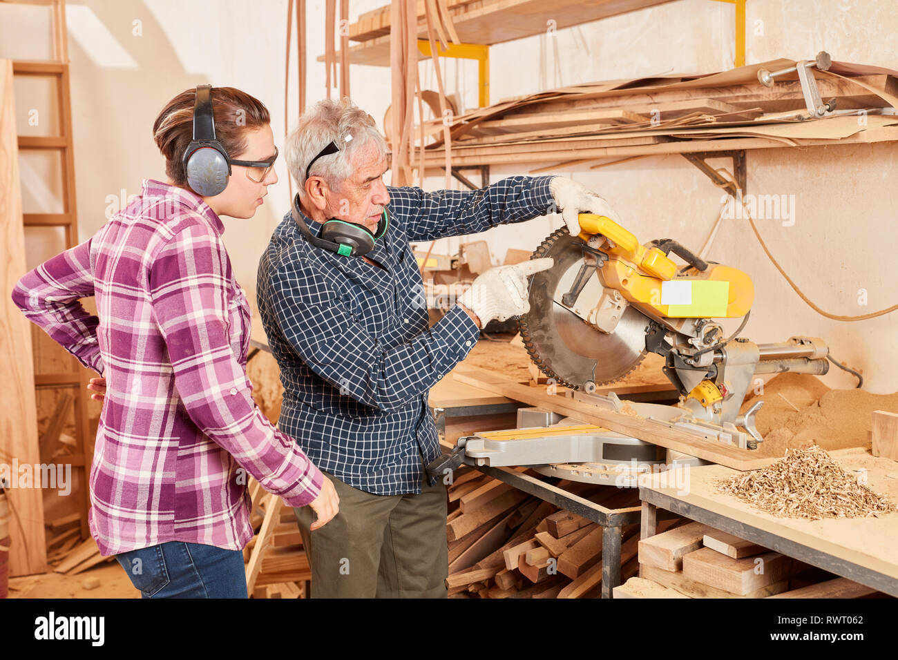 Young woman as a carpenter. Apprentice and master work together on the chop saw Stock Photo Alamy