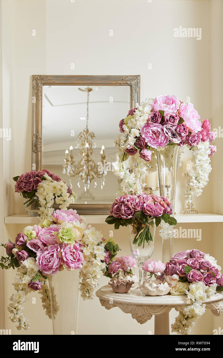 Mirror White And Purple Flowers In Glass Vases On Table And Shelf