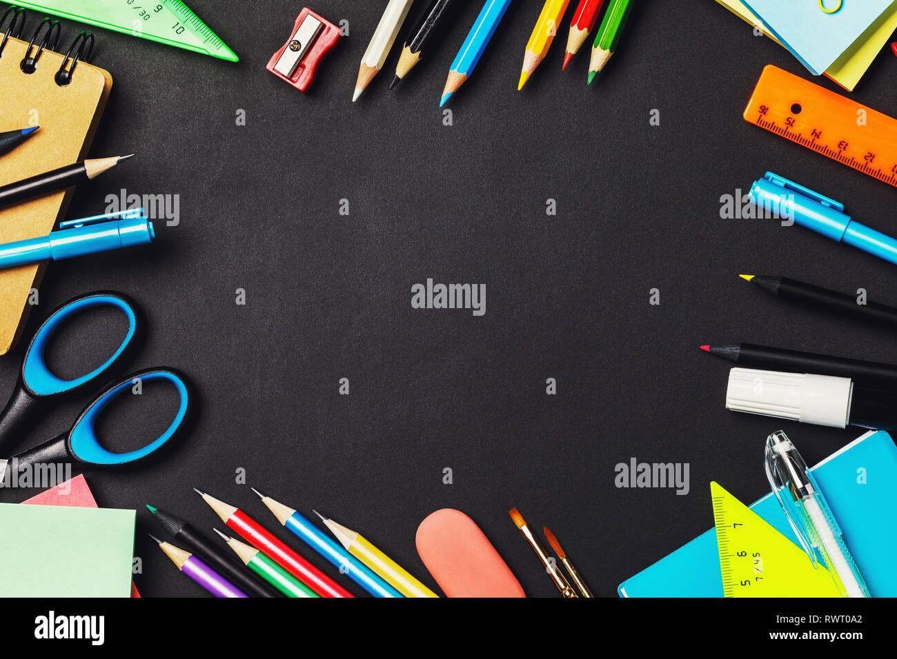 Blackboard with school supplies and copy space in the middle, top view ...