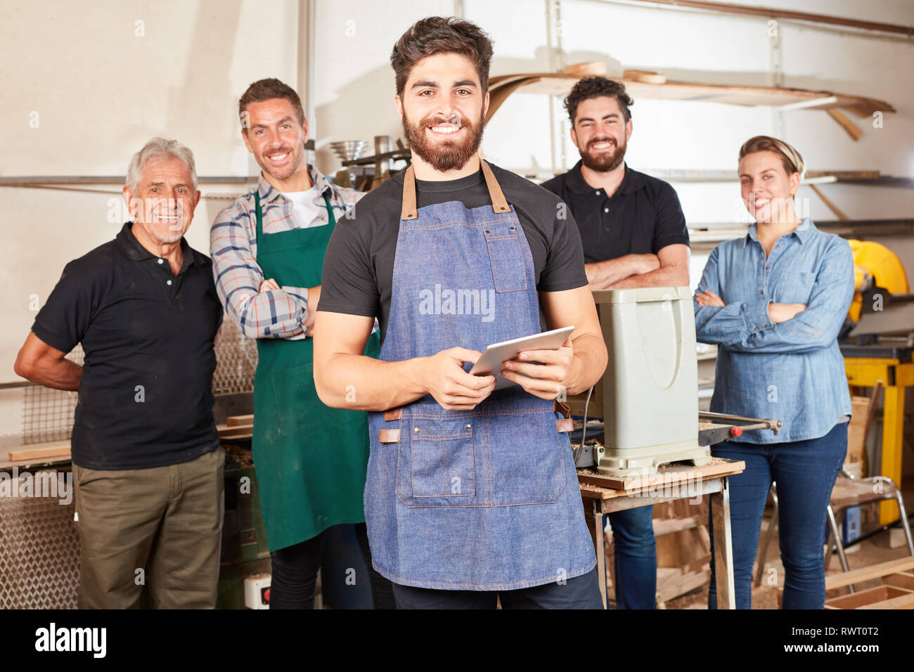 Young man as a craftsman apprentice using tablet computer in his joiner's shop Stock Photo