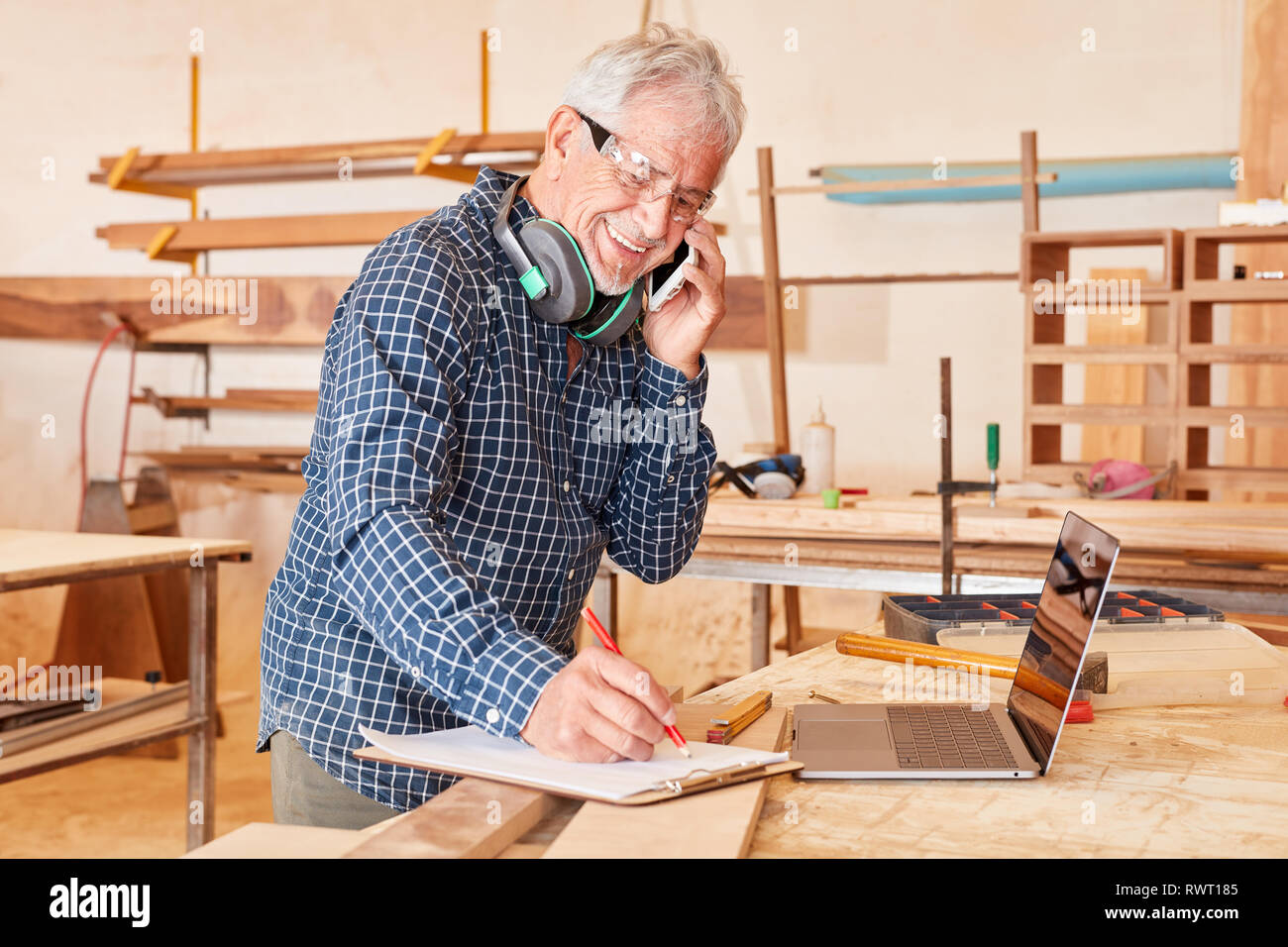 Craftsman with mobile phone and checklist in his carpentry or joinery