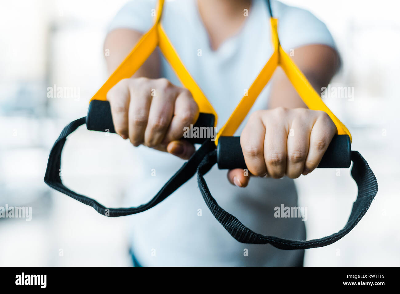 selective focus of plus size girl training arms with suspension straps