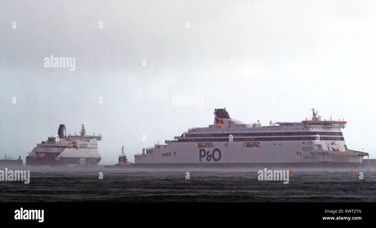 A tugboat manoeuvres a P&O ferry at the Port of Dover in Kent during stormy conditions. Stock Photo