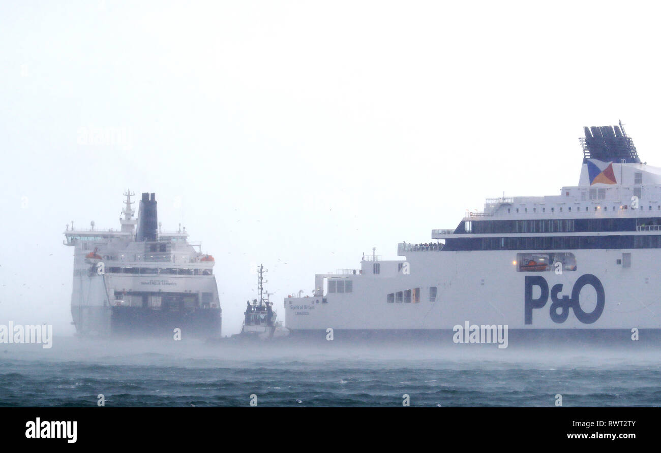 A tugboat manoeuvres a P&O ferry at the Port of Dover in Kent during stormy conditions. Stock Photo