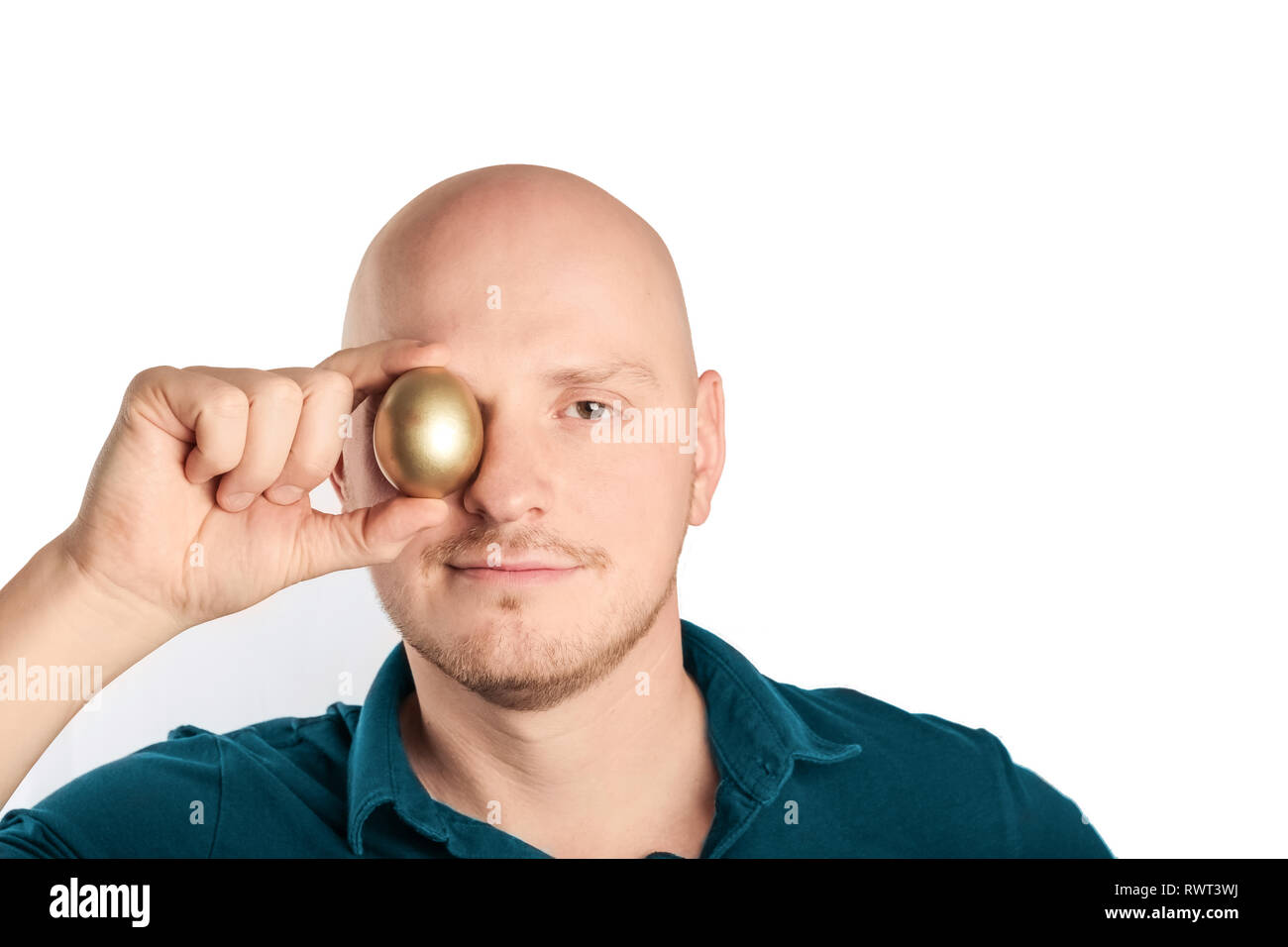 Young man with blue shirt holding golden egg to the camera, feeling confident., feeling confident. Studio shot on a white background Stock Photo