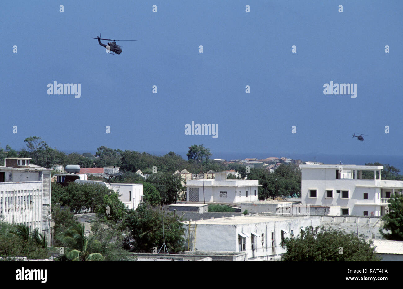 20th October 1993 A U.S. Army Bell AH-1 Cobra attack helicopter and an OH-58 Kiowa Scout Observation helicopter patrol low above the rooftops of Mogadishu, Somalia. Stock Photo