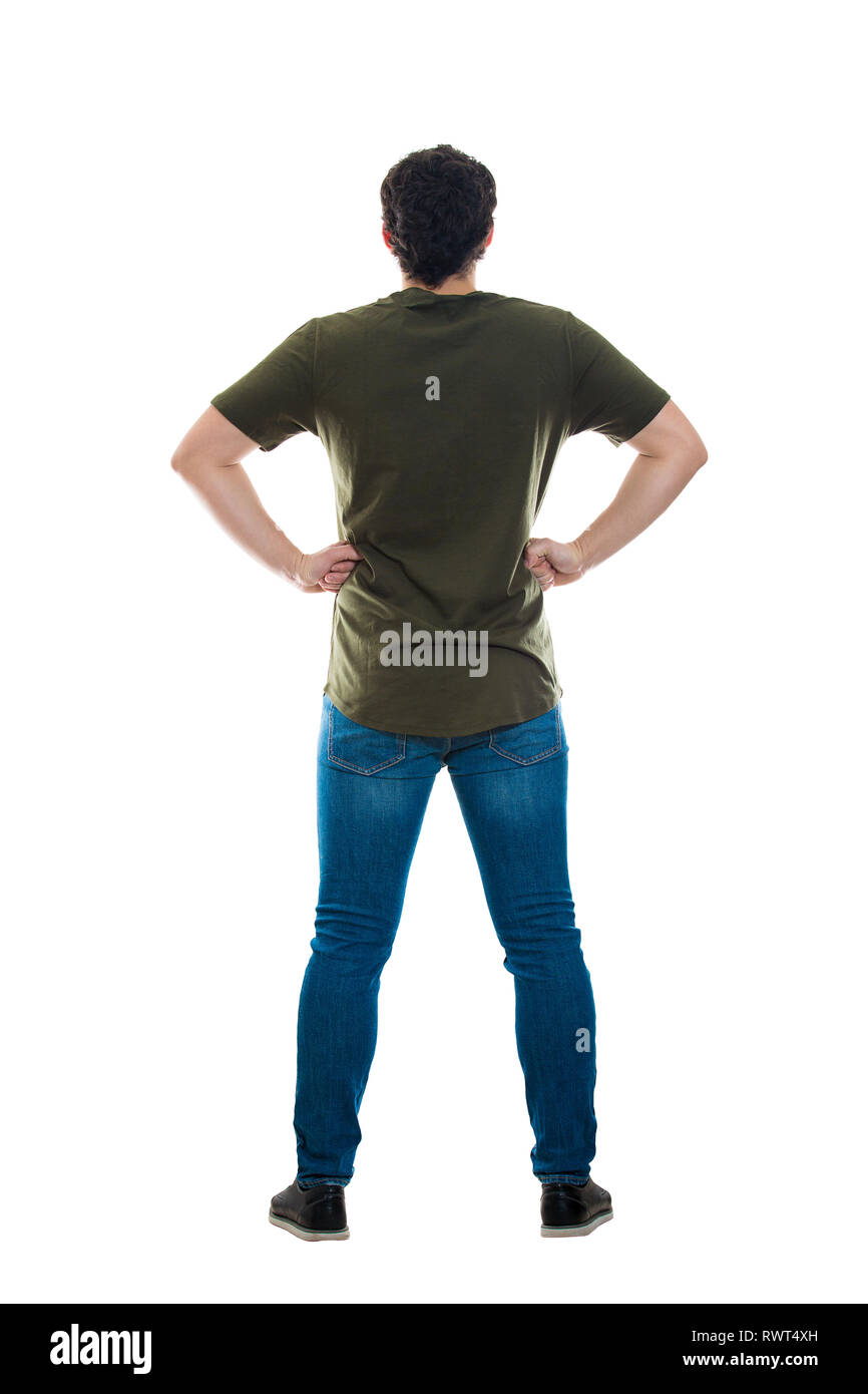 Full length rear view of casual young man standing with hands on hips looking ahead isolated over white background. Backside male body confident gestu Stock Photo