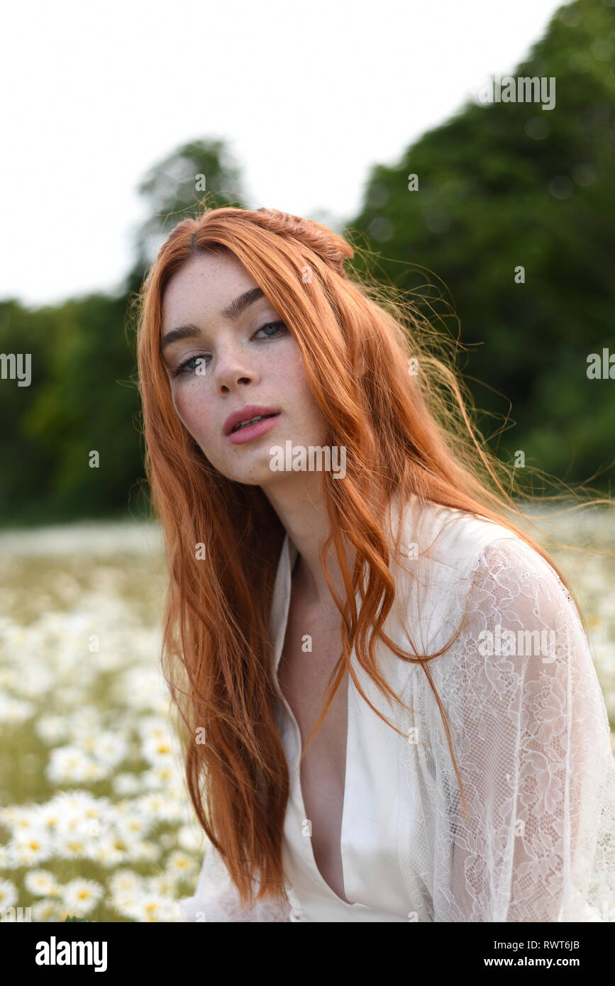 A Beautiful Red Haired Girl In A Long White Dress Poses In The Middle Of A Daisy Beautiful Girl In A Field Stock Photo Alamy