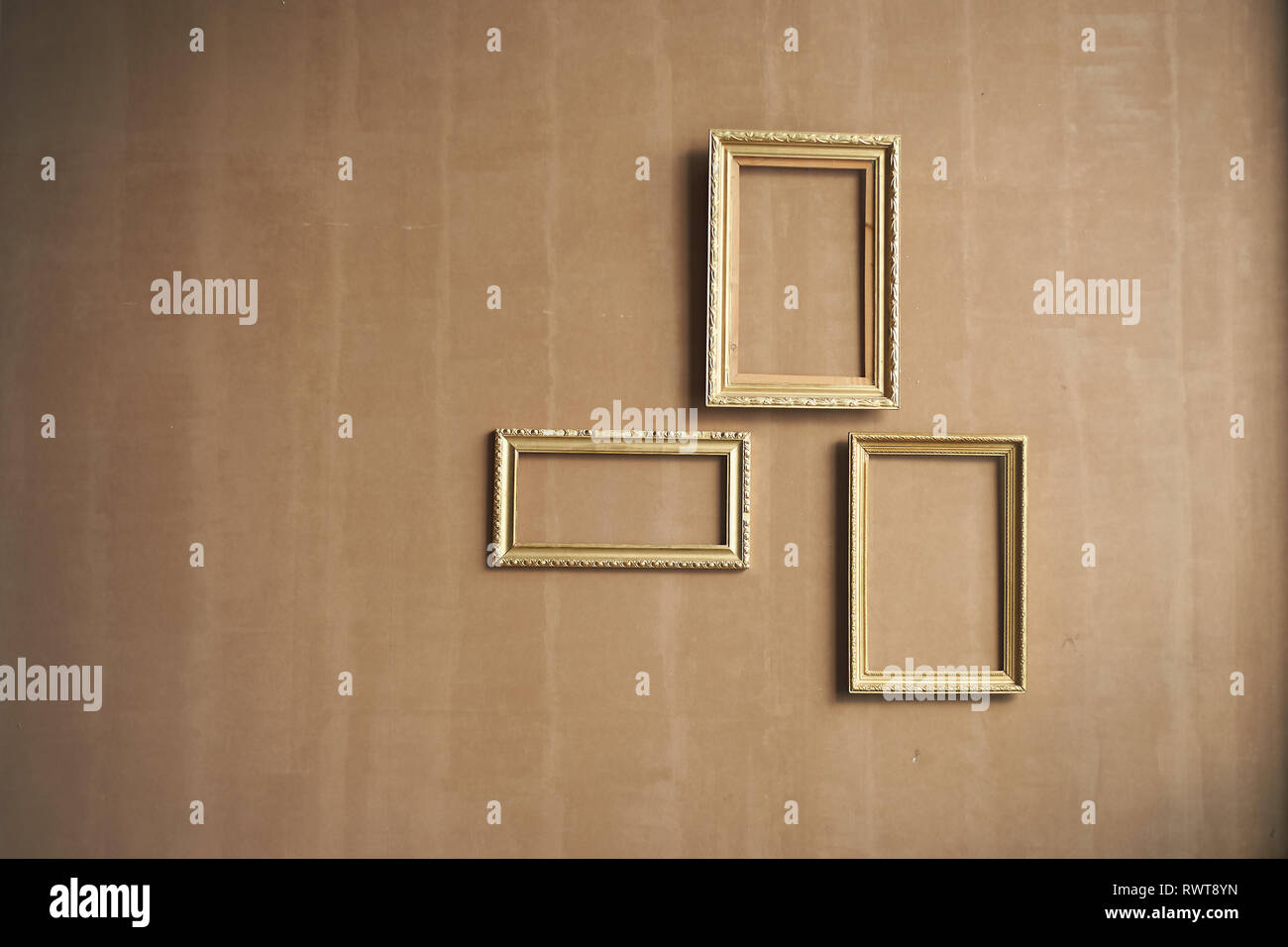Minimalism.Brown wall with empty gold frames. Stock Photo