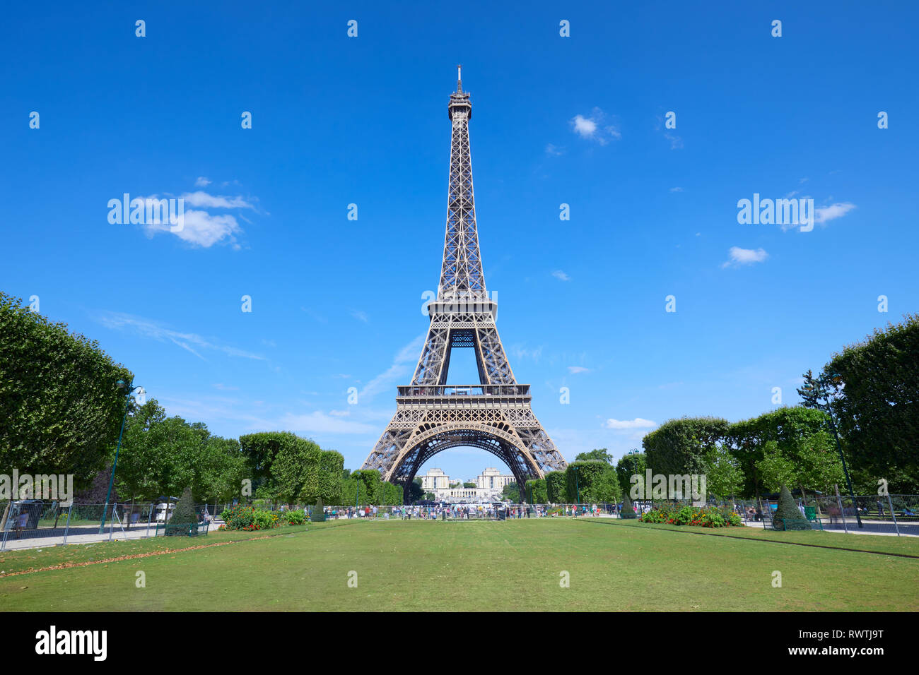 Eiffel Tower in Paris and empty green field of Mars meadow in a sunny summer day, clear blue sky Stock Photo