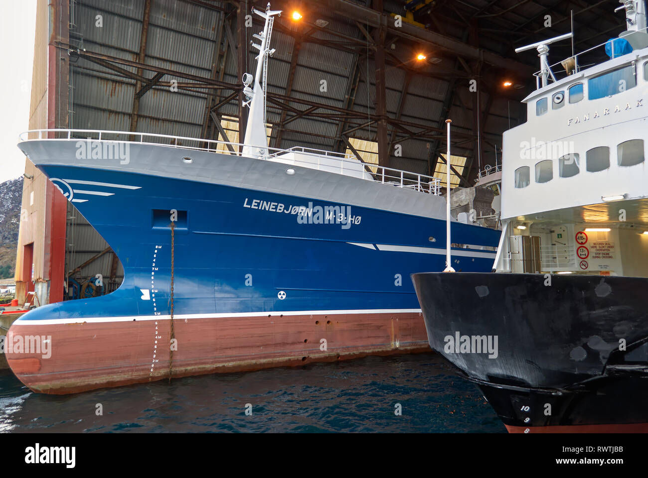 A Trawler and an Inter Island Car Ferry under the covered work area of the Batbygg Shipyard in Maloy, Norway having work done to them. Stock Photo