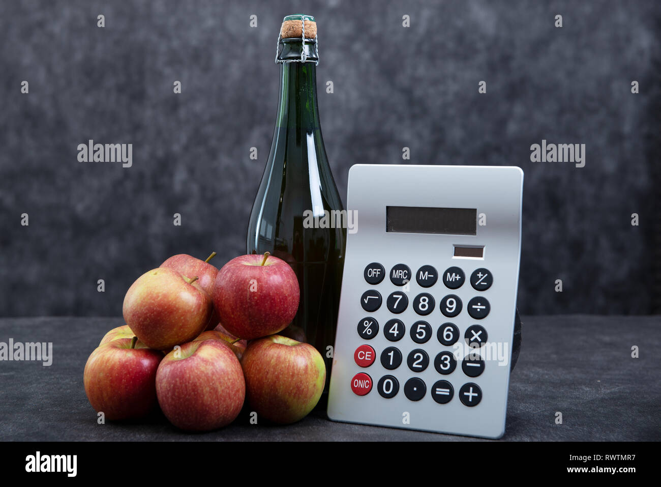 organic apples, a bottle of cider and calculator, expensive concept