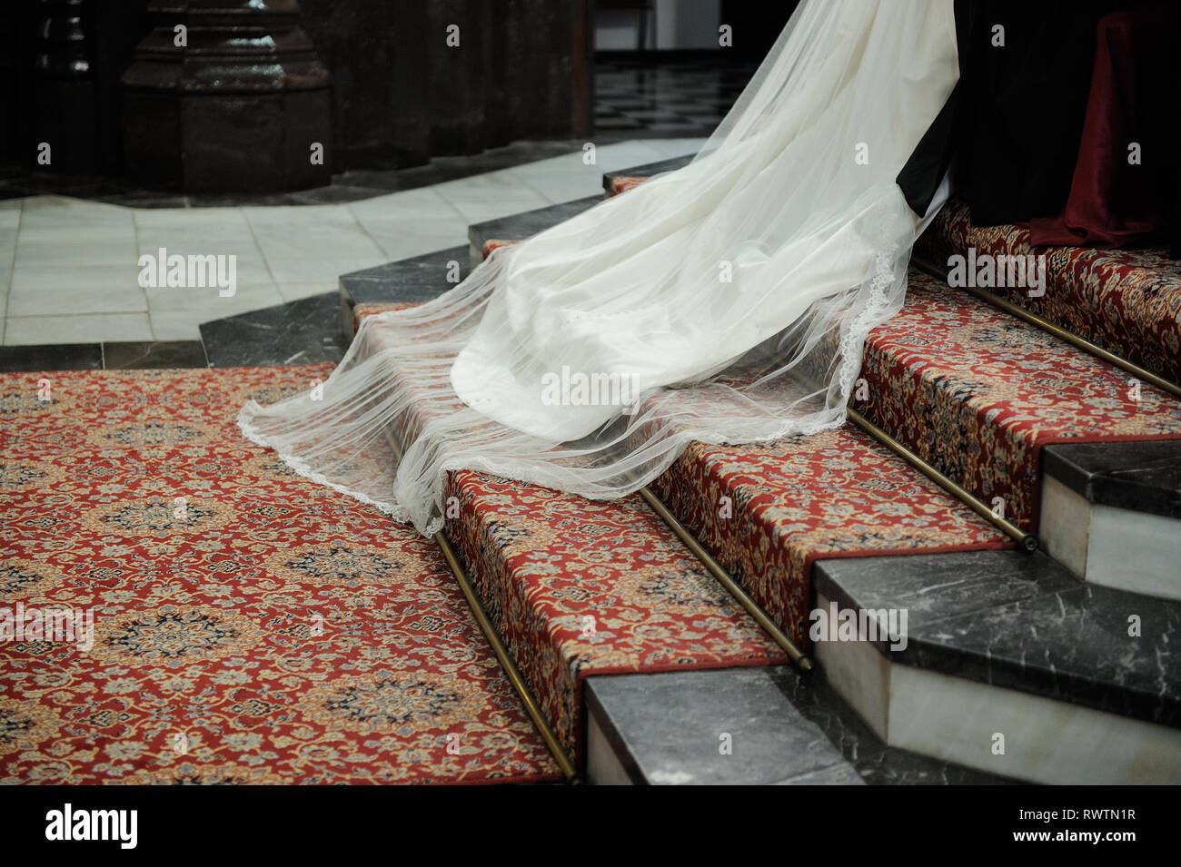 tail of white wedding dress on red carpet with steps Stock Photo