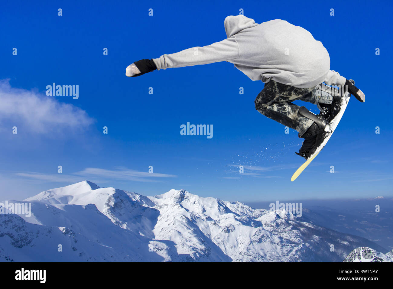 Extreme Jumping Snowboarder at jump above mountains at sunny day Stock Photo