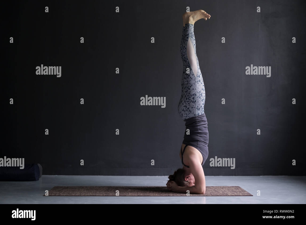 Young sporty woman practicing yoga, doing headstand exercise, salamba sirsasana pose, working out Stock Photo