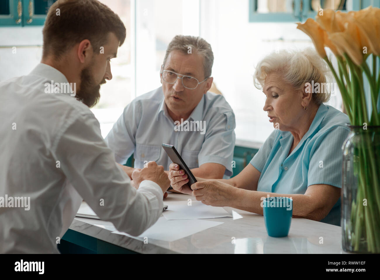 Financial advisor helps old couple to count a budget, sitting at the
