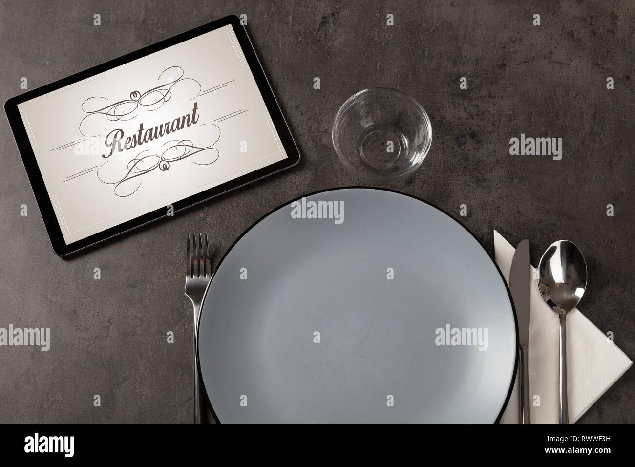 Tablet with stylish restaurant logo and laid table  Stock Photo