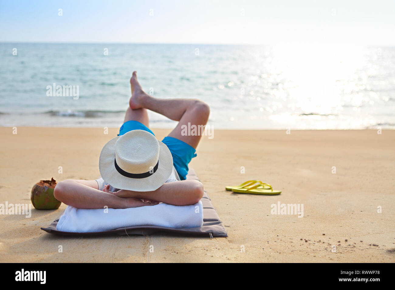 Young man in the hat with coconut cocktail on the beach Stock Photo
