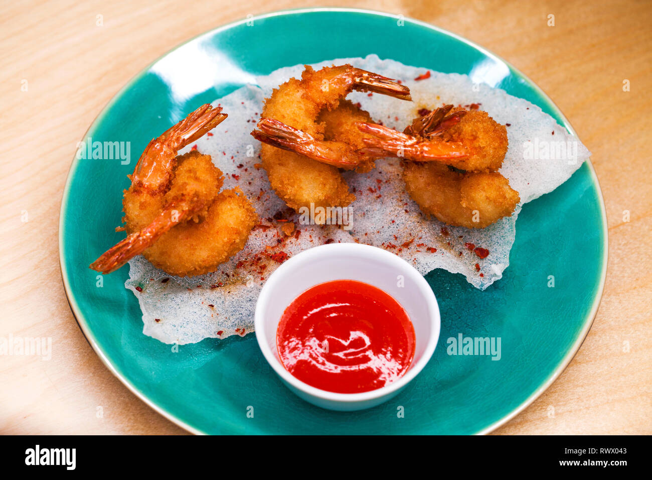 Restaurant dish. Deep fried king prawns with spicy sauce on a blue