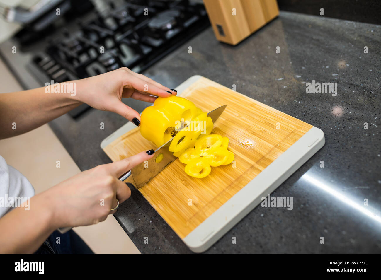 Happy young woman cutting fresh vegetables in kitchen Stock Photo