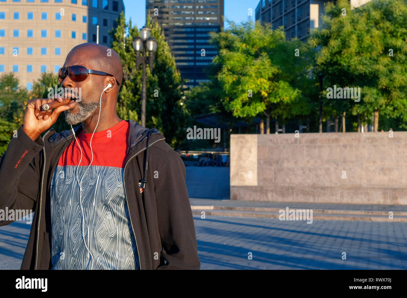 An American smokes a cigar in Battery Park. This park is in the south-west side of downtown Manhattan, adjacent to the Financial District and Ground Z Stock Photo