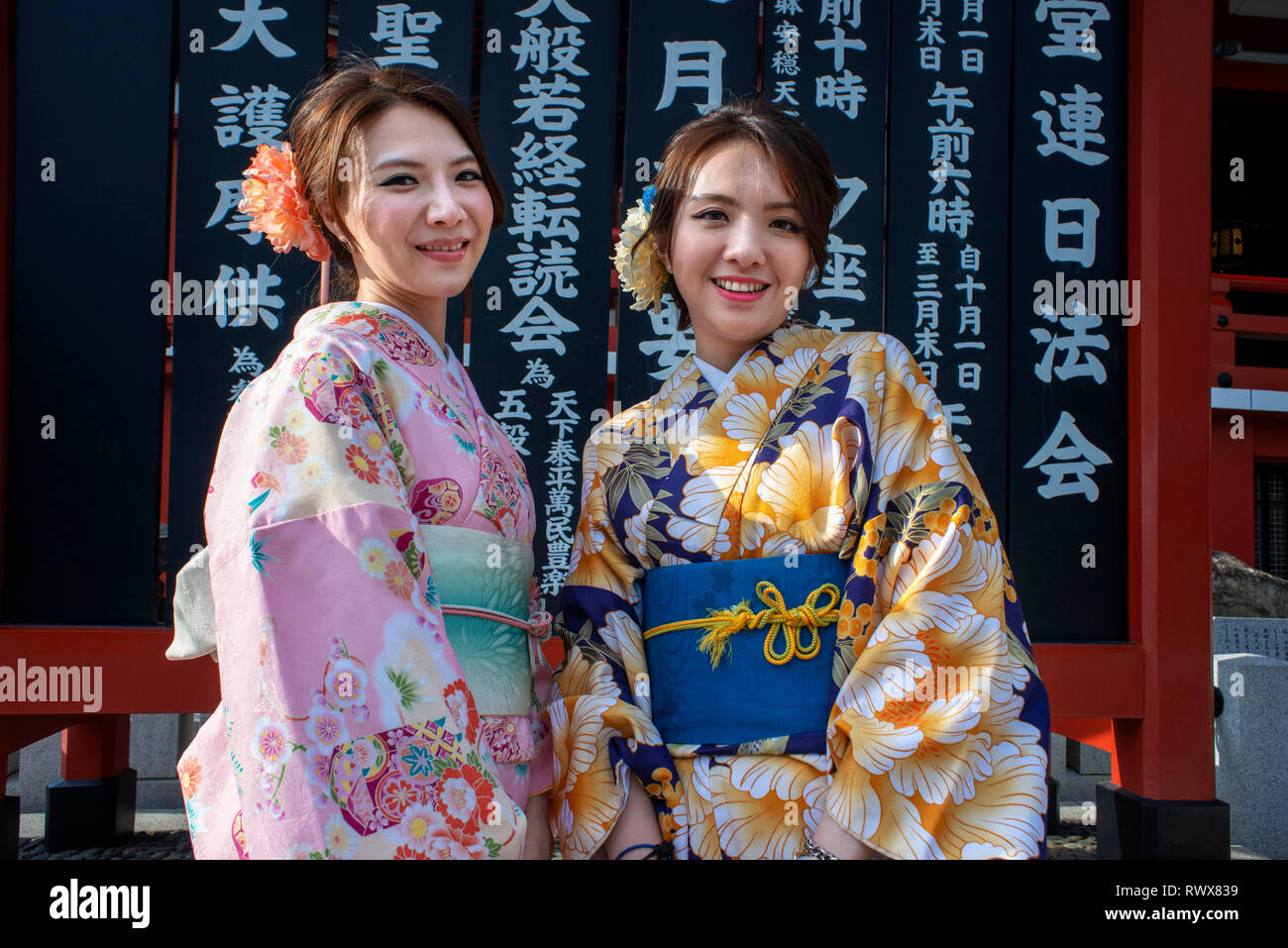 Women wearing kimono, the national tradition costume of Japan, walking on Nakamise dori, a street with food and souvenirs shops. Senso-ji Buddhist Tem Stock Photo