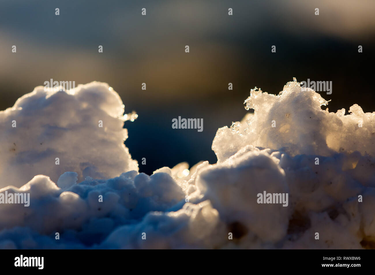Defocused background with chunky focused snow foreground lit by sunrise Stock Photo