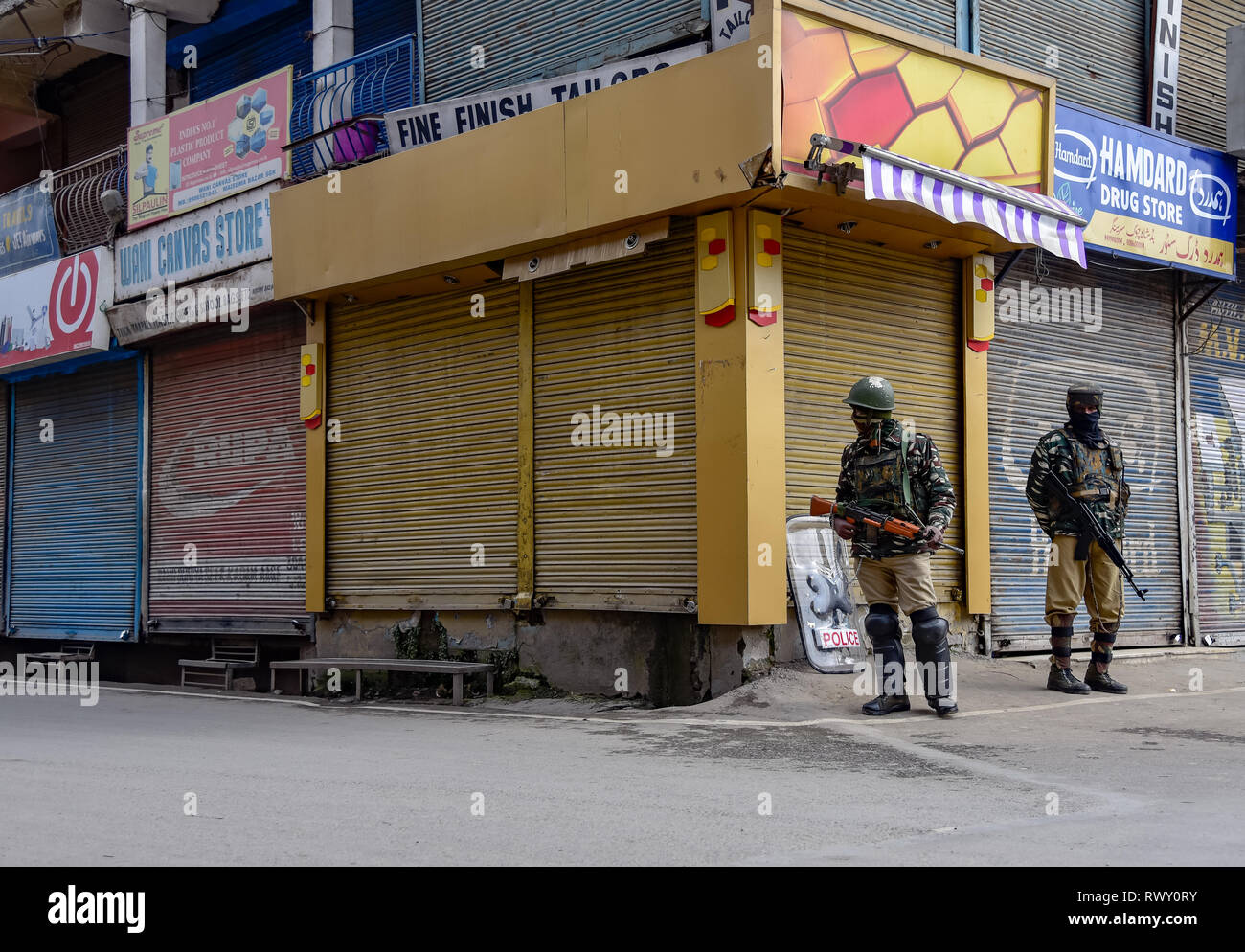 Indian paramilitary troopers are seen standing on guard in-front of closed shop during the shut-down in Maisuma area of Srinagar. A shut-down is being observed in Maisuma area of Srinagar city. Jammu and Kashmir Liberation Front chairman Yasin Malik who was detained on February 22 was booked under Public Safety Act (PSA) and shifted to Kot Balwal jail in Jammu earlier today. Stock Photo
