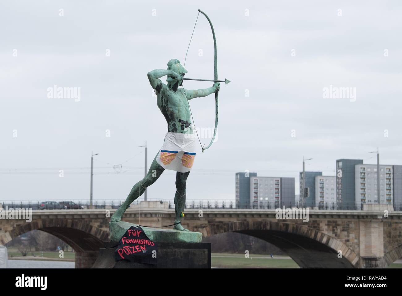 Dresden, Germany. 08th Mar, 2019. A toilet brush as well as an apron and a black fabric with the inscription 'Für Feminismus Putzen' hang on the sculpture 'Archer' by Ernst Moritz Geyger. The action falls on the International Women's Day, which is celebrated on the same day. Credit: Sebastian Kahnert/dpa-Zentralbild/dpa/Alamy Live News Stock Photo