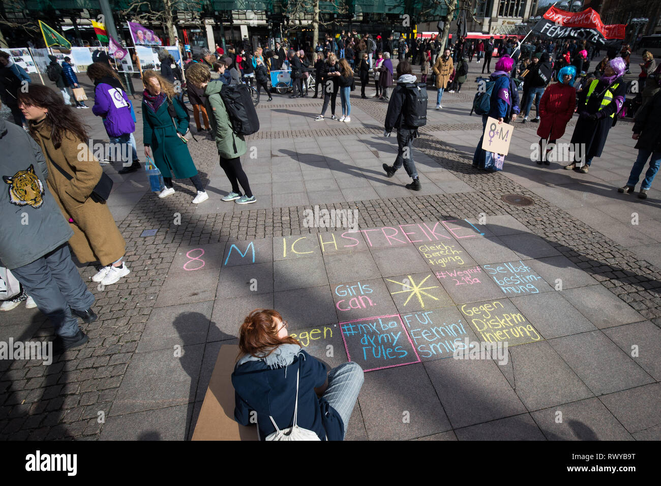 Hamburg, Germany. 08th Mar, 2019. A young woman writes her protest with chalk on the floor at a demonstration on International Women's Day at the town hall market. Parties, unions, and women's rights organizations have called for a rally for more equality in front of the Hamburg City Hall on World Women's Day. At the same time, the 'Hamburg Alliance for the International March 8 Strike' called on all 'women, lesbians, non-binary, trans and inter persons' to lay down their work. Credit: Christian Charisius/dpa/Alamy Live News Stock Photo