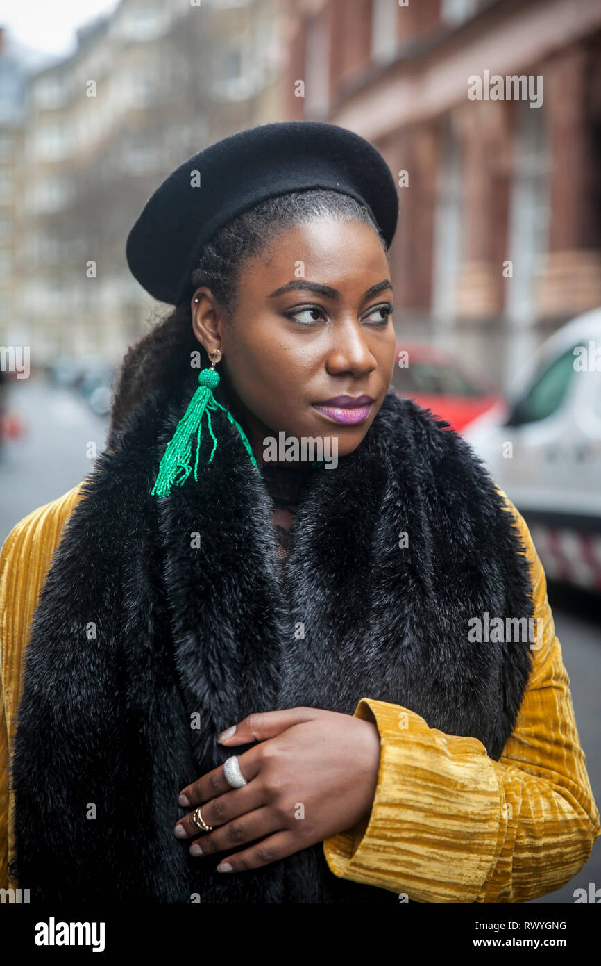 LONDON - FEBRUARY 15, 2019: Stylish attendees gathering outside 180 The Strand for London Fashion Week. Girl in a yellow corduroy coat with a fur coll Stock Photo
