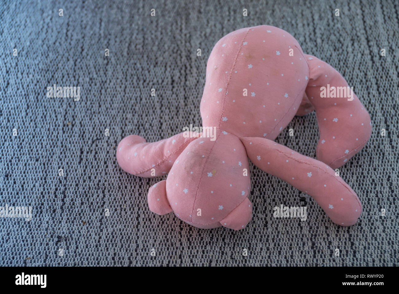 Discarded child's old soft toy isolated on a grey carpet image with copy space Stock Photo
